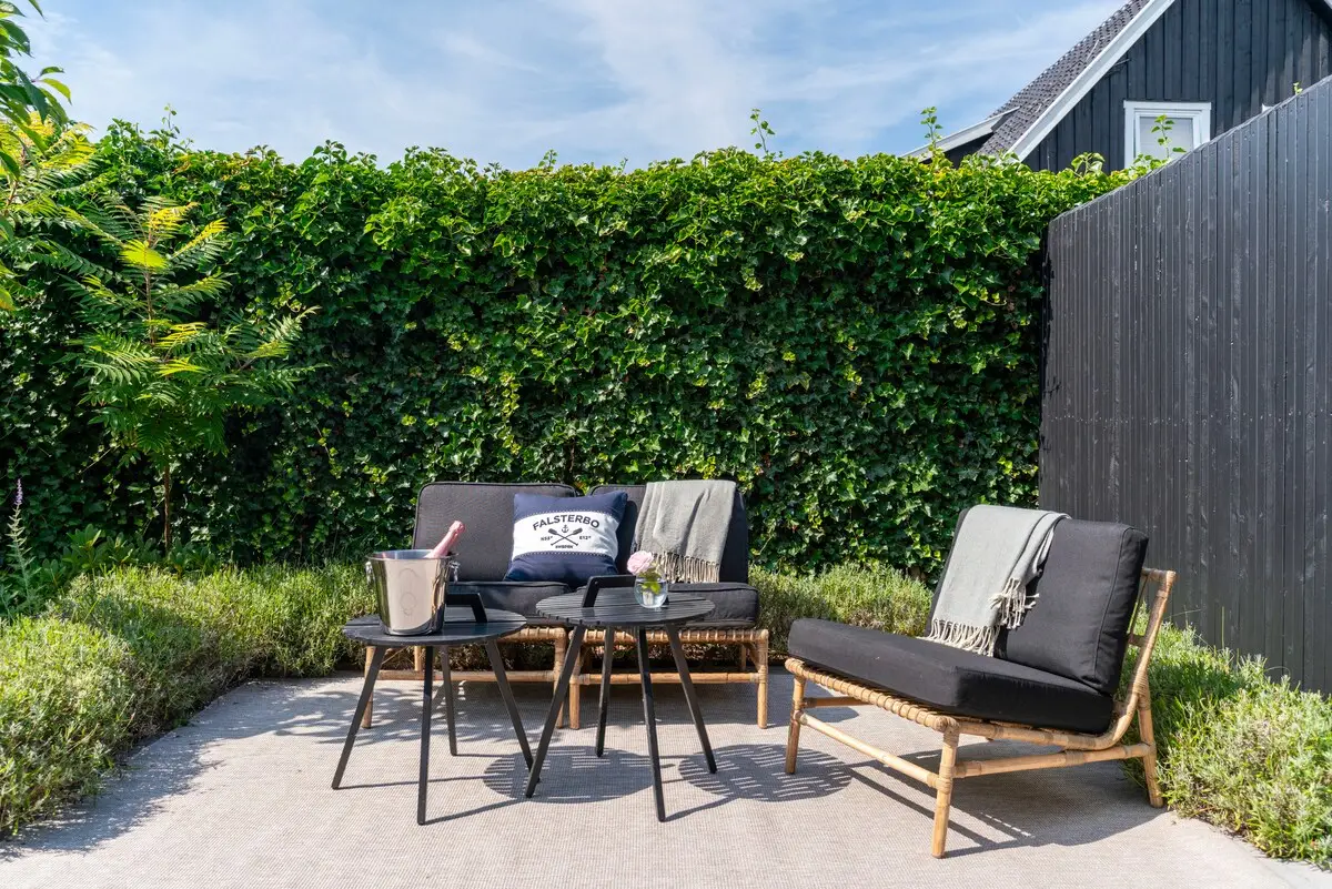 Sunny private patio with lounge seating, surrounded by green hedges